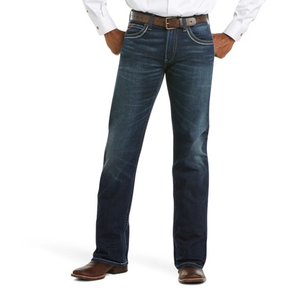 A man wearing jeans and boots is standing with his hands in his pockets.