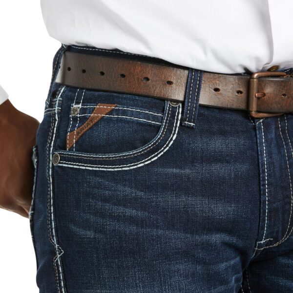 A man wearing jeans and a brown belt.