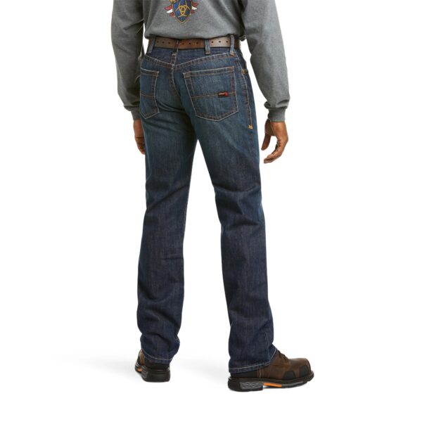 A man wearing jeans and boots is standing up.