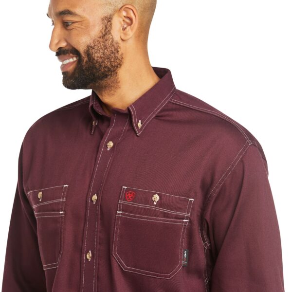 A man wearing a maroon shirt with white stitching.