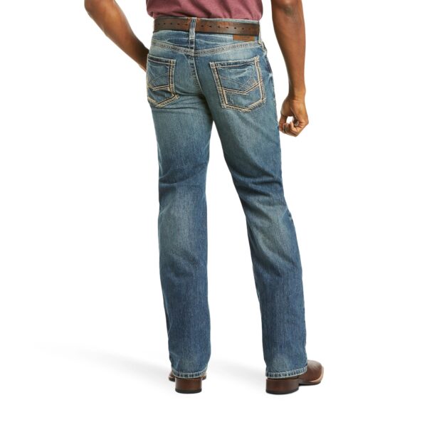 A man wearing jeans and boots is standing.