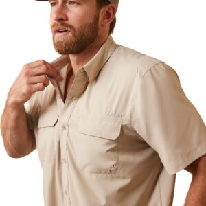 A man in tan shirt and hat putting on his tie.