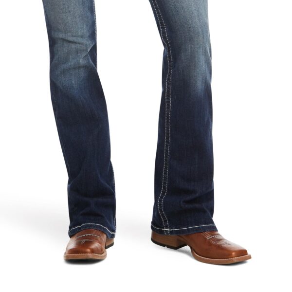 A person wearing brown shoes and jeans.