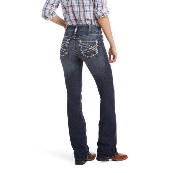 A woman wearing jeans and boots is standing up.