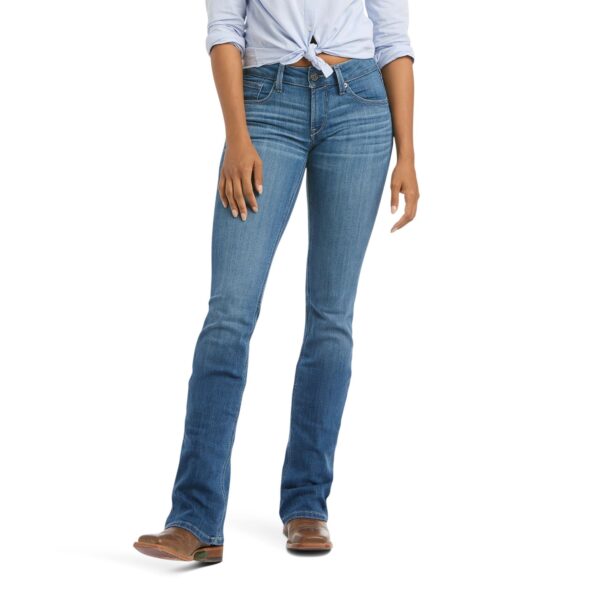 A woman wearing jeans and boots is standing up.