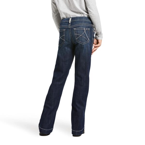 A woman wearing jeans and boots is standing.