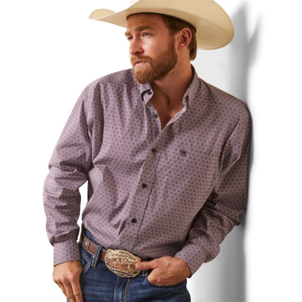 A man in cowboy hat and jeans leaning against wall.