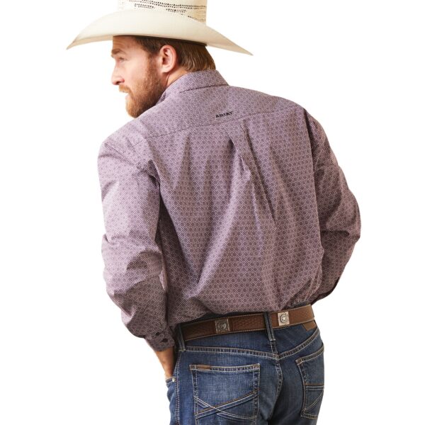 A man in cowboy hat and jeans standing with his hands on the back of his pants.