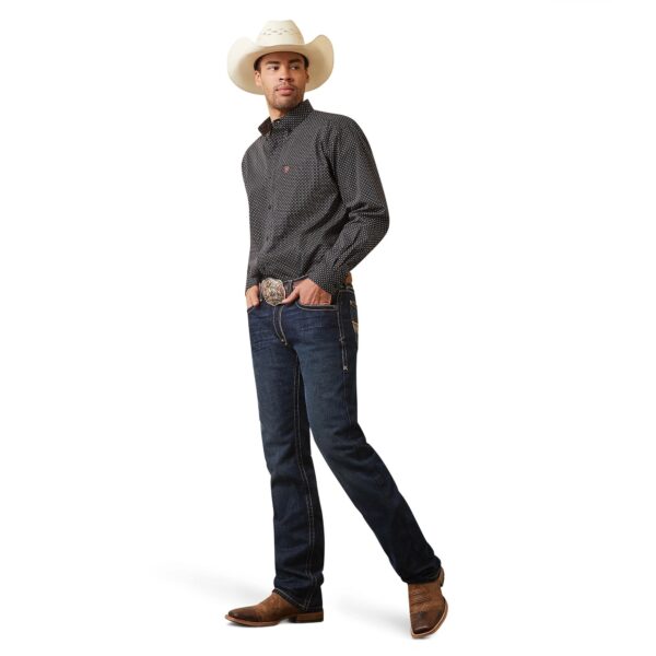 A man in cowboy hat and jeans standing with hands in his pockets.