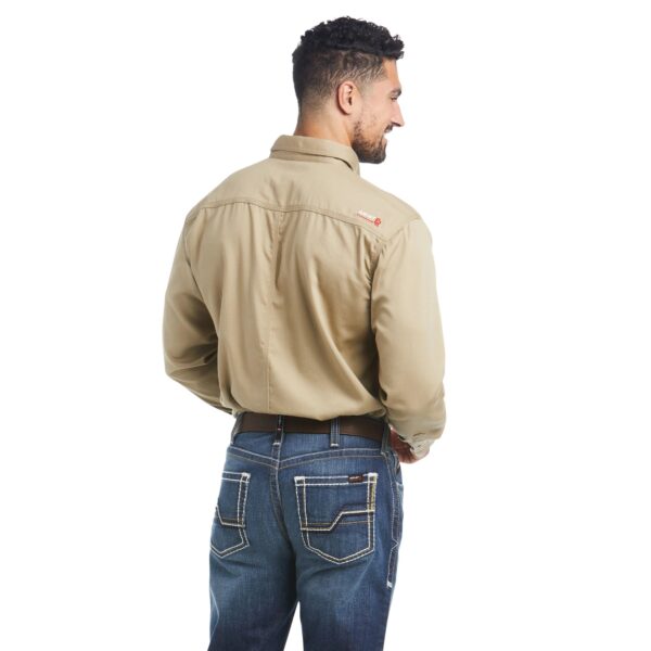 A man in jeans and a tan shirt is standing up