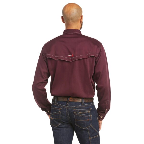 A man wearing jeans and a maroon shirt.