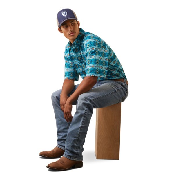 A man sitting on top of a box wearing jeans and a blue shirt.