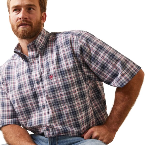 A man in plaid shirt and jeans posing for the camera.