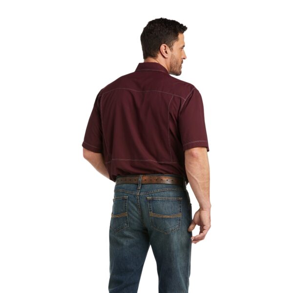 A man wearing jeans and a maroon shirt.