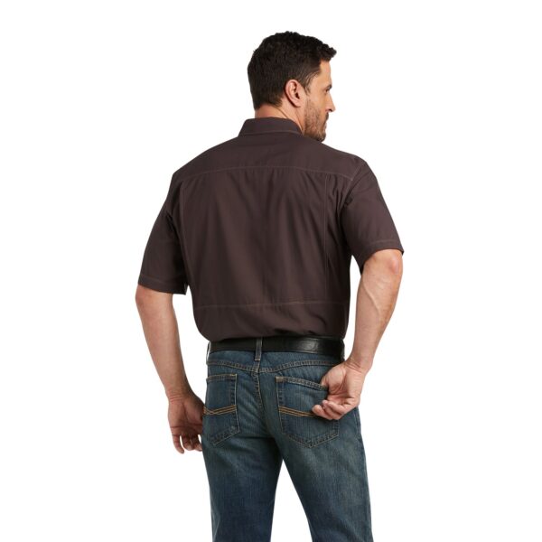 A man wearing jeans and brown shirt is standing.