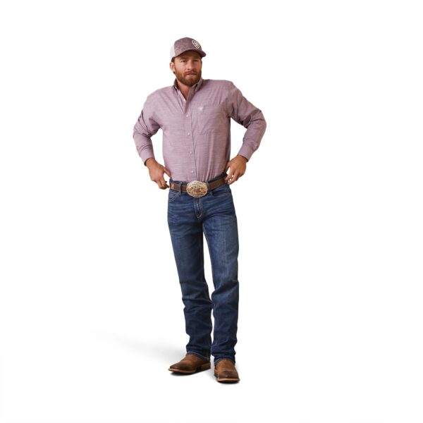 A man in jeans and a hat standing with his hands on his hips.