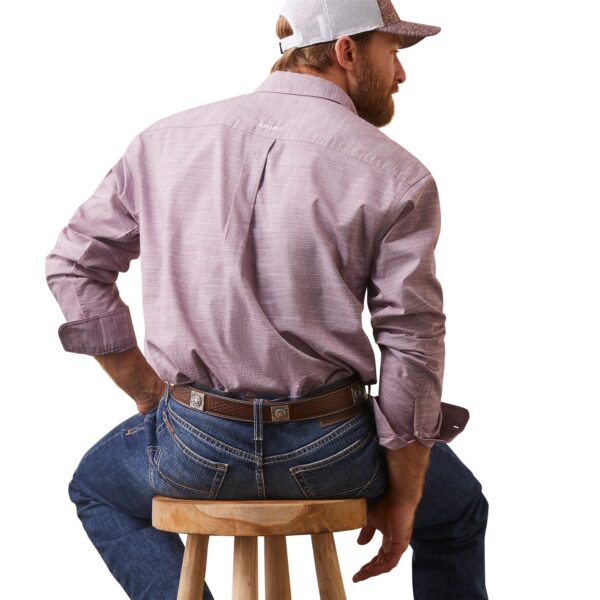 A man sitting on top of a stool wearing jeans.