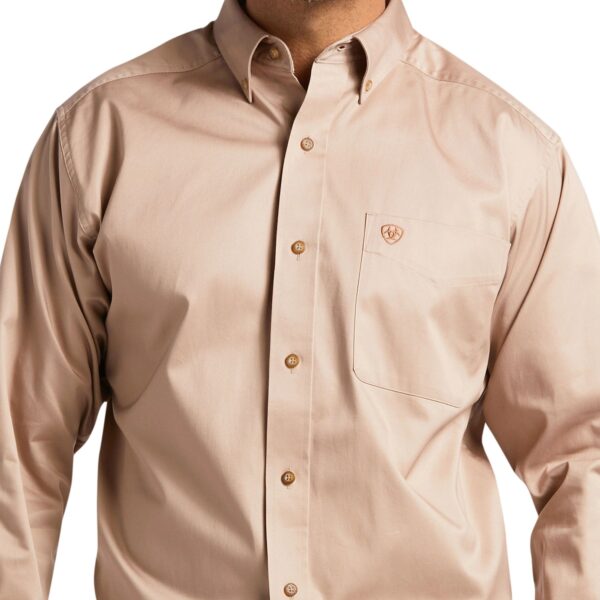 A man wearing a tan shirt with buttons down the front.