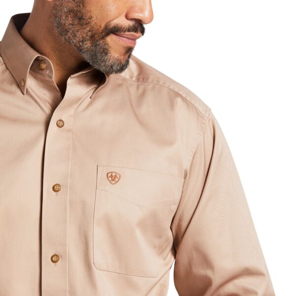 A man wearing a tan shirt with a beard.