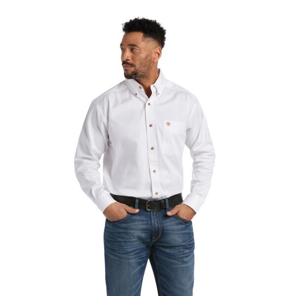 A man wearing jeans and white shirt with hands in his pockets.