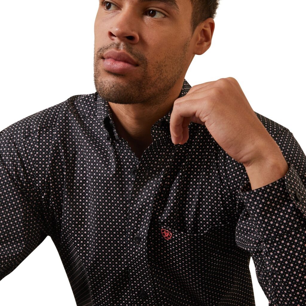 A man in black shirt holding his hand up to his face.