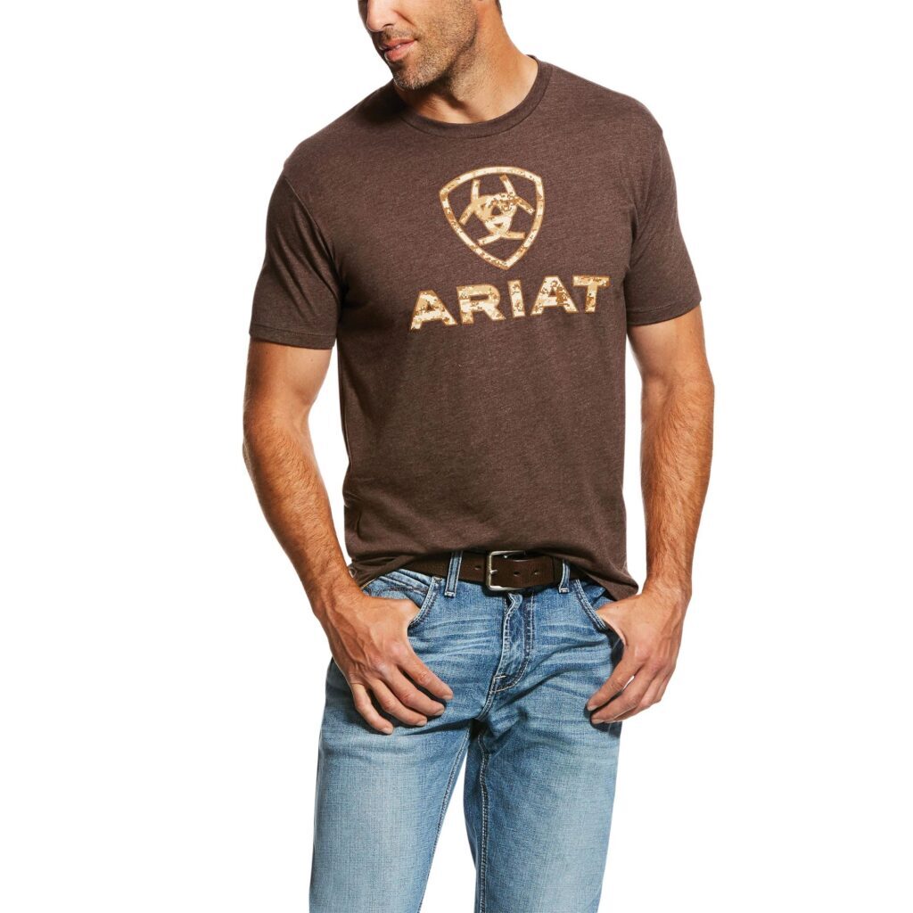 A man wearing jeans and brown t-shirt with the word " ariat " on it.