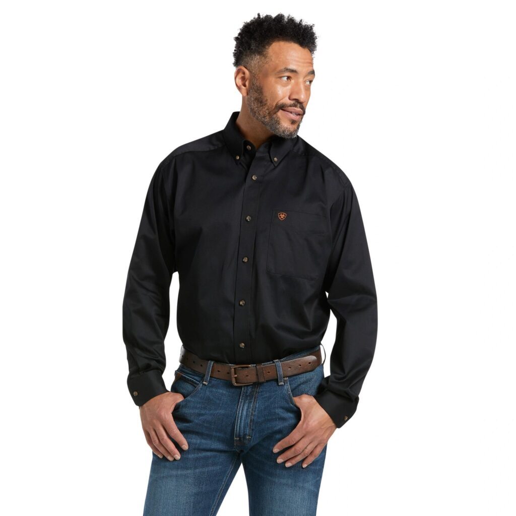 A man wearing jeans and black shirt with hands on his hips.